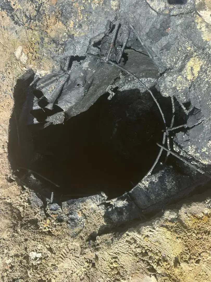 Open manhole with exposed reinforcement during renovation