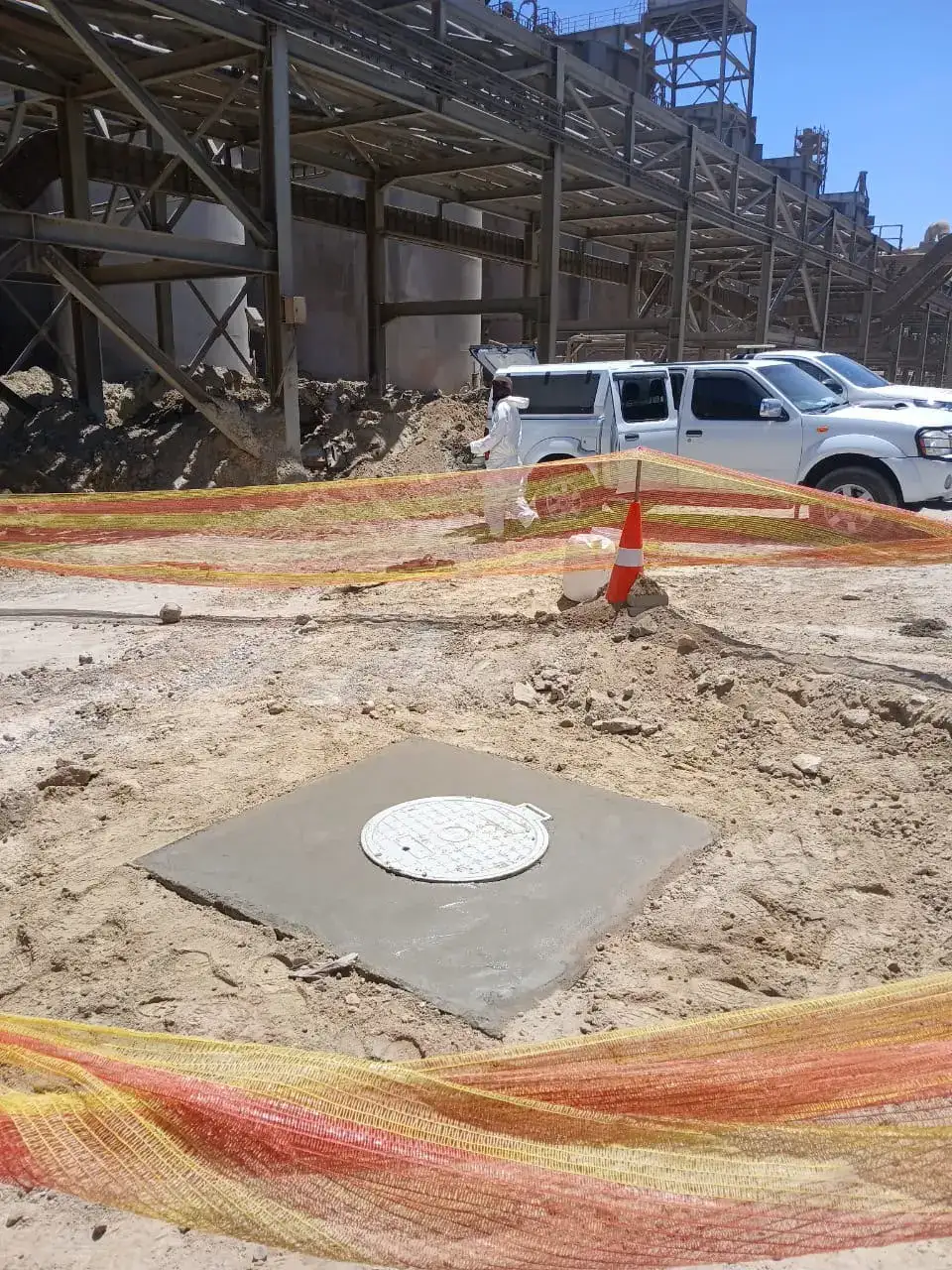 Renovated manhole with a new concrete slab and cover, safety netting around the area