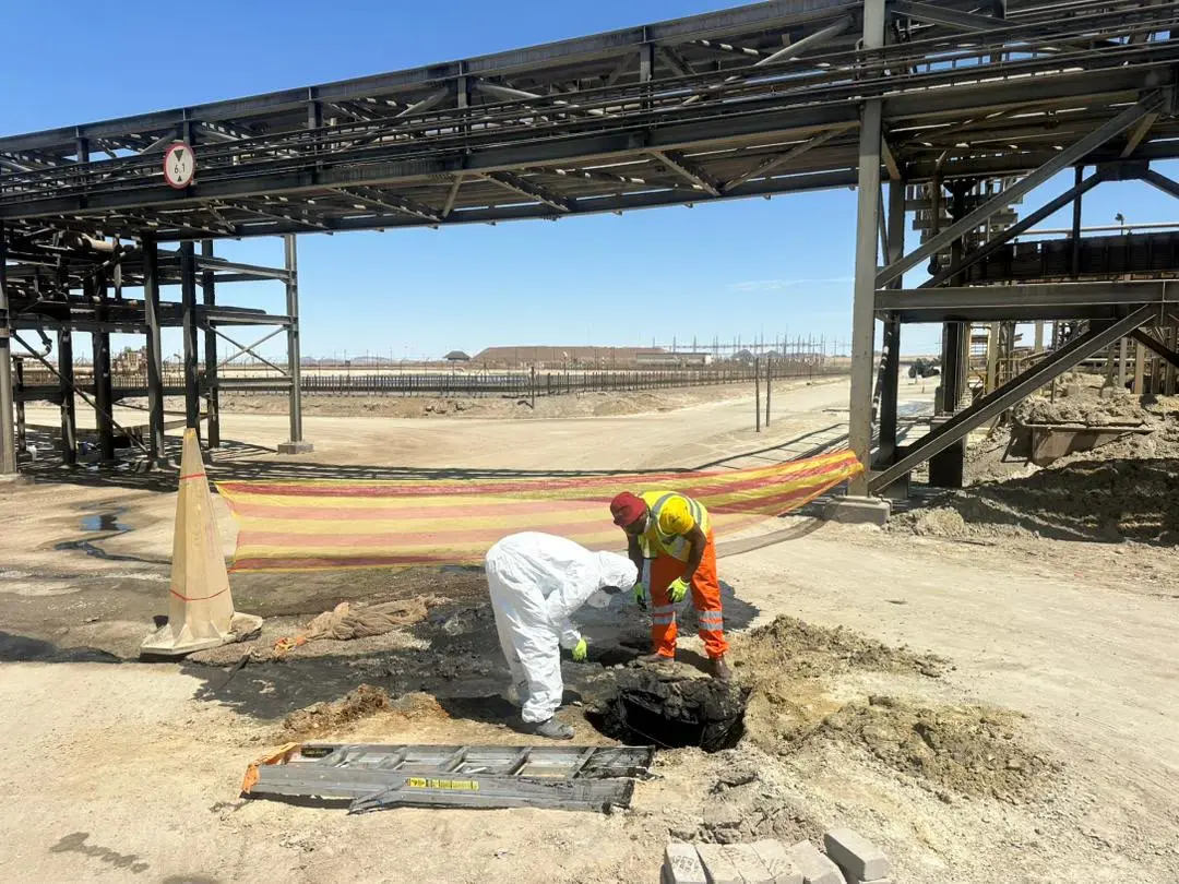 Two workers in protective gear renovating a manhole at an industrial plant