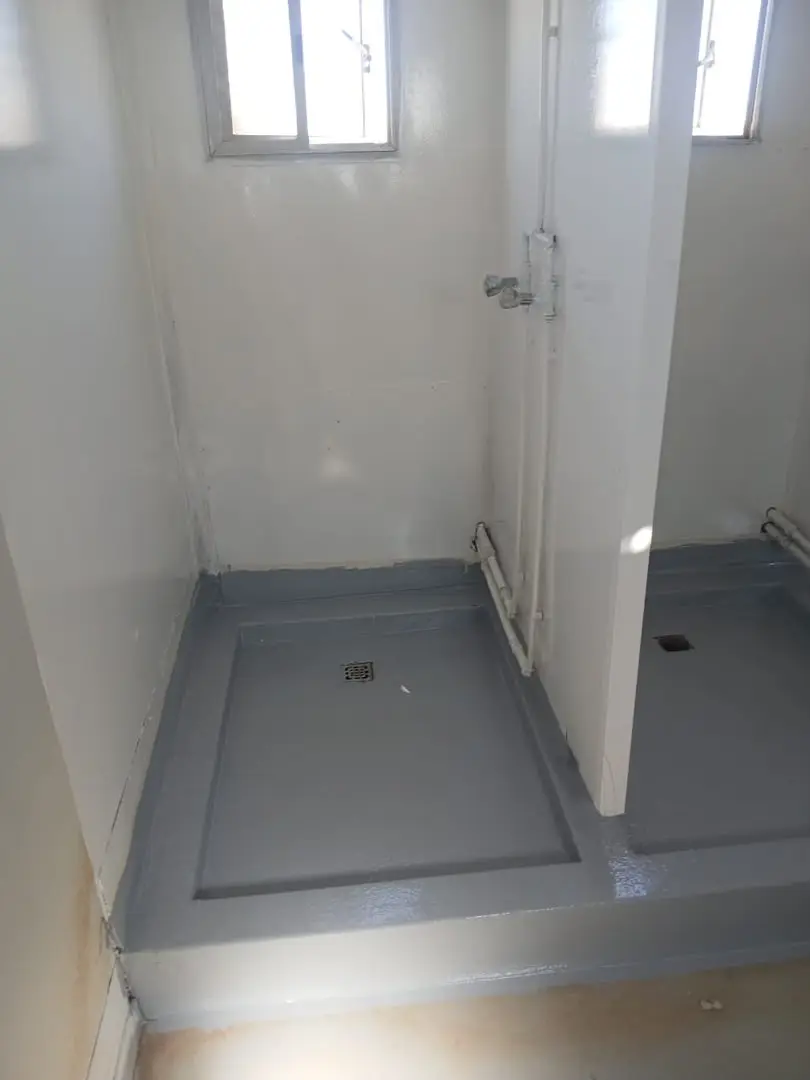 Shower cubicle with a coated floor, drain and new white pipework