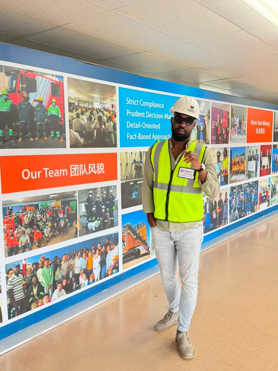 Man in a hi-vis vest and hard hat posing in a mine facility corridor