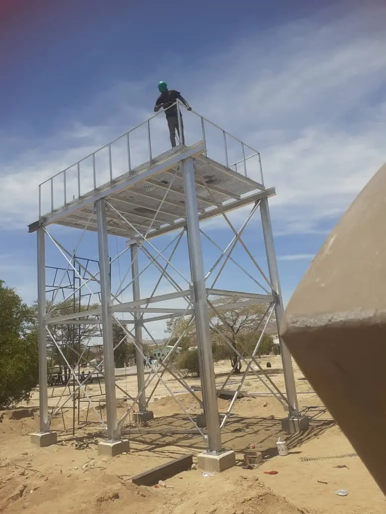 Galvanised steel tower with a worker on the platform, second angle