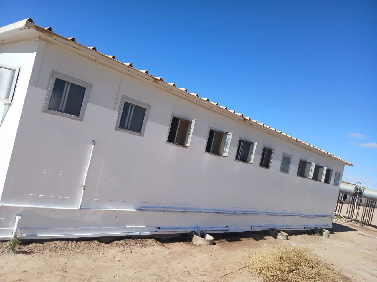 Renovated shower block: white prefabricated building with painted walls and new drainage pipework